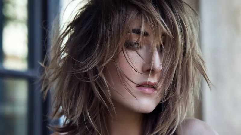 femme avec une coupe wolf cut volumineuse et texturée sur cheveux mi-longs