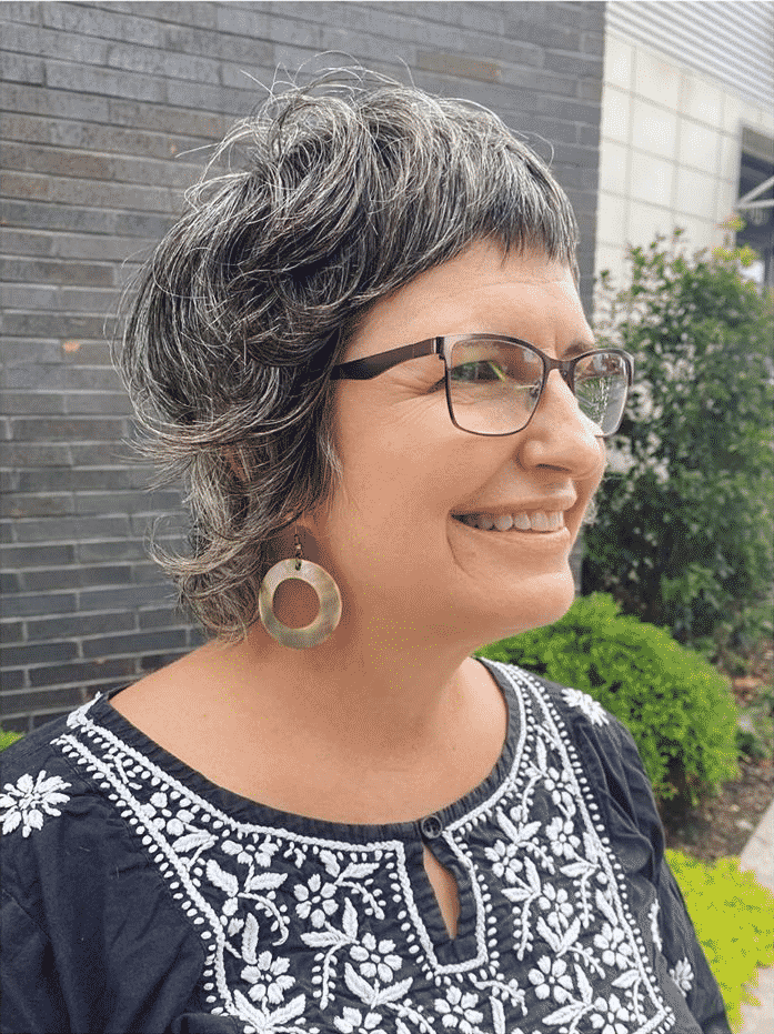 Femme de plus de 50 ans avec des cheveux fins et une coupe au rasoir avec des lunettes.