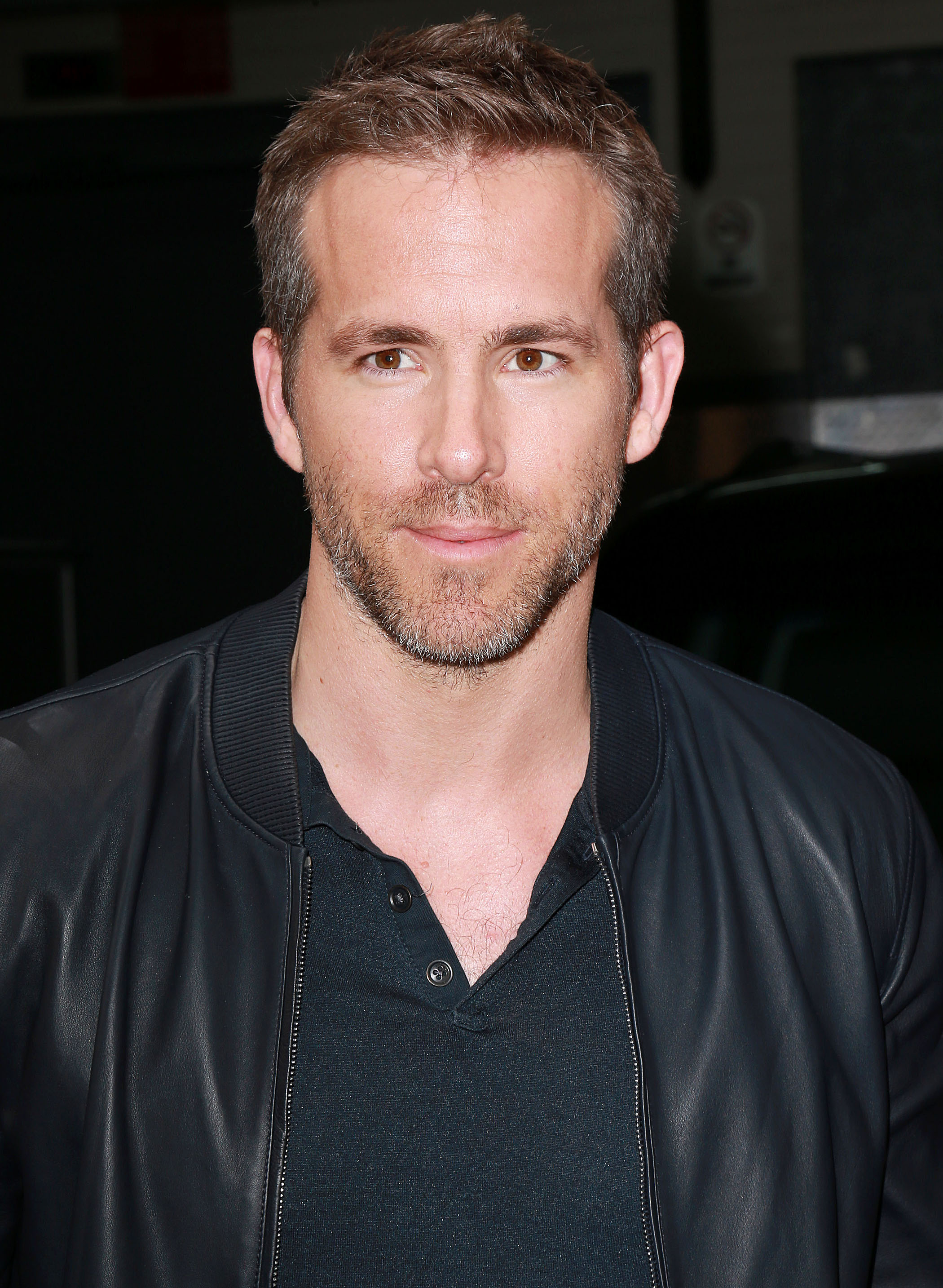 Coupe de cheveux Ivy League: Ryan Reynolds aux cheveux bruns dans une coupe de cheveux Ivy League, vêtu d'un haut noir et d'une veste