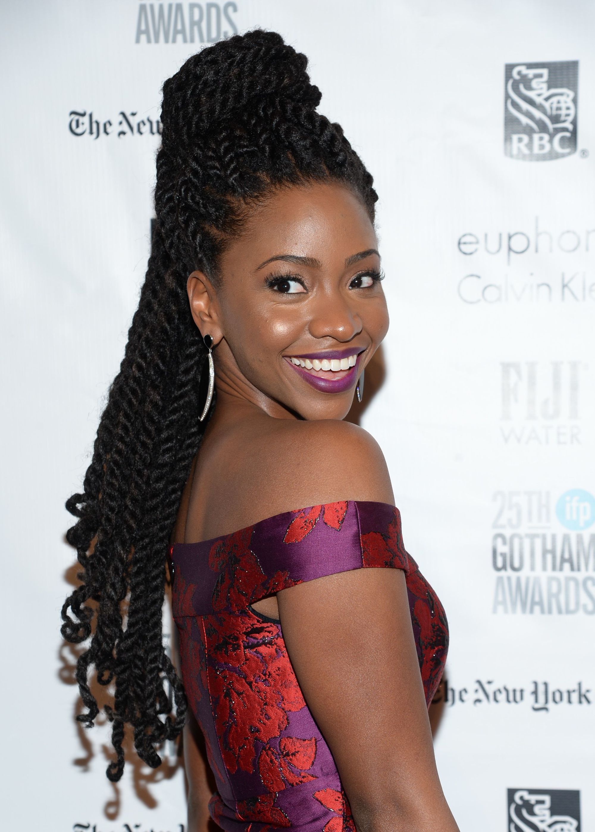 Shot of Teyonah Paris with half-up marley twists styled with curly ends, wearing a purple dress