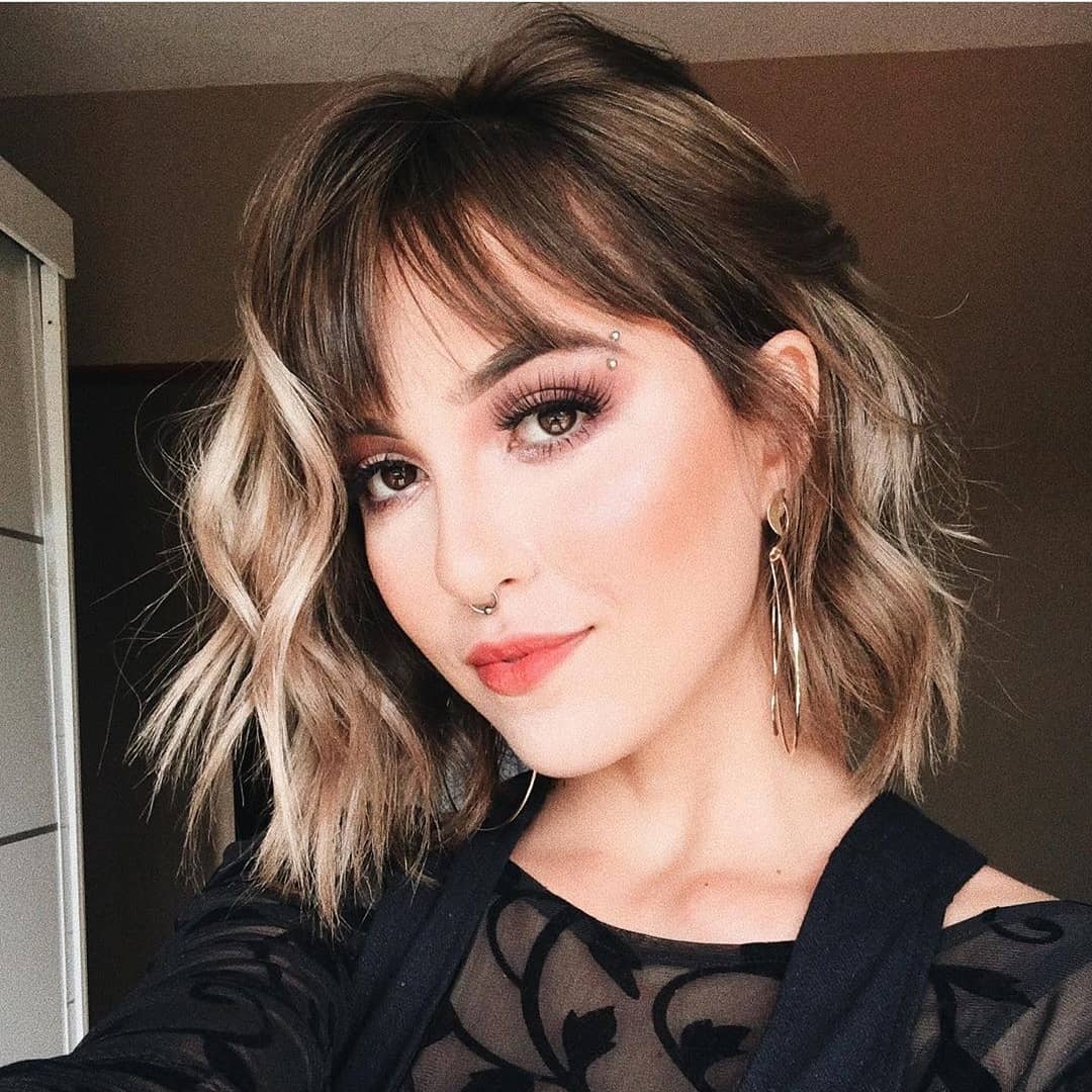 Woman with layered short hair and wispy bangs