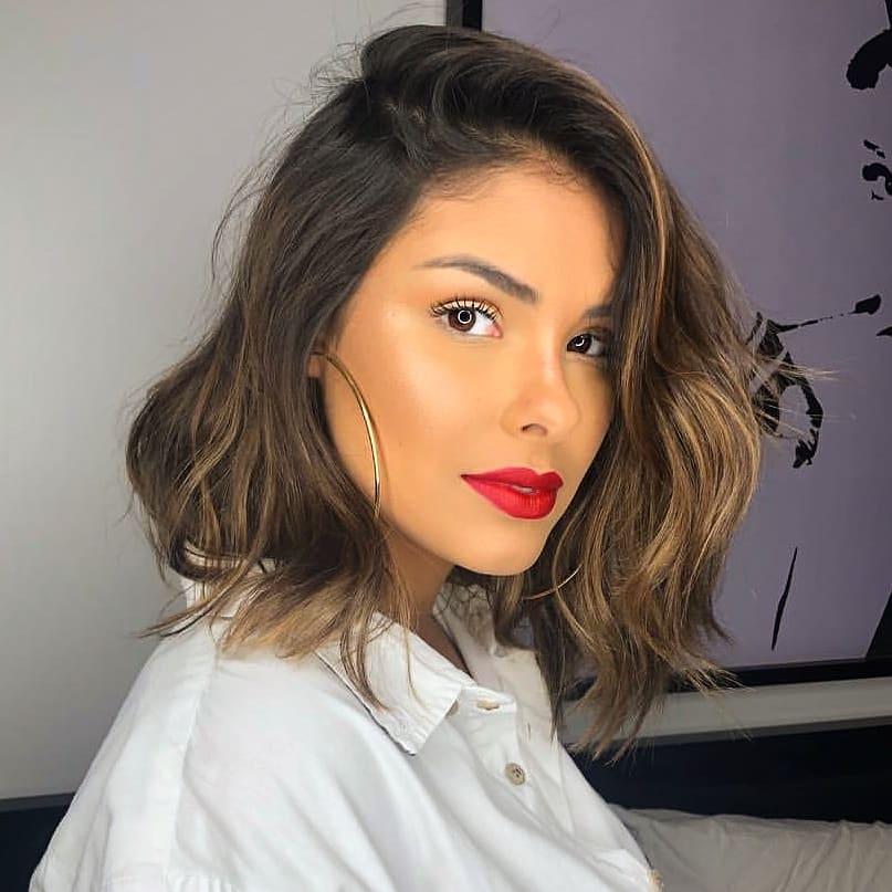 Woman with medium dark layered bob with caramel highlights