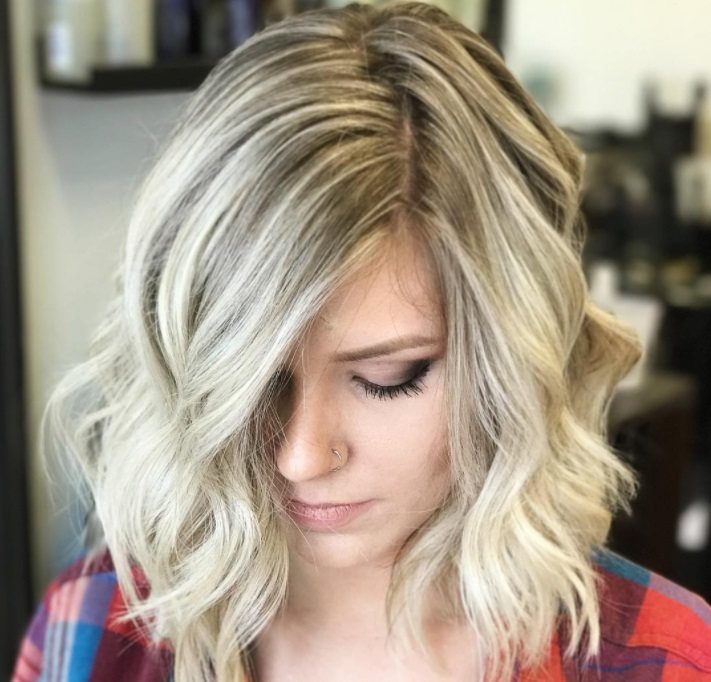 Layered bob: Photo from above of a woman with a light ash blonde curly asymmetric lob