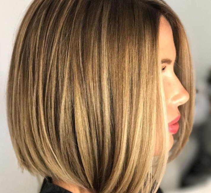 Layered bob: Side profile of a woman with a bronde highlighted sleek bob with layers