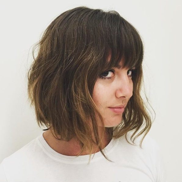 Layered bob: Woman with a brunette shaggy bob with a fringe, wearing a white t-shirt