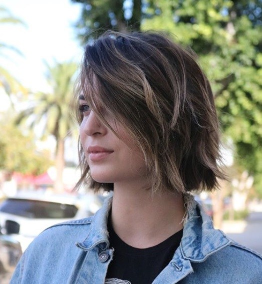 Layered bob: Outdoor shot of a woman with a brunette tousled side-swept bob with highlights