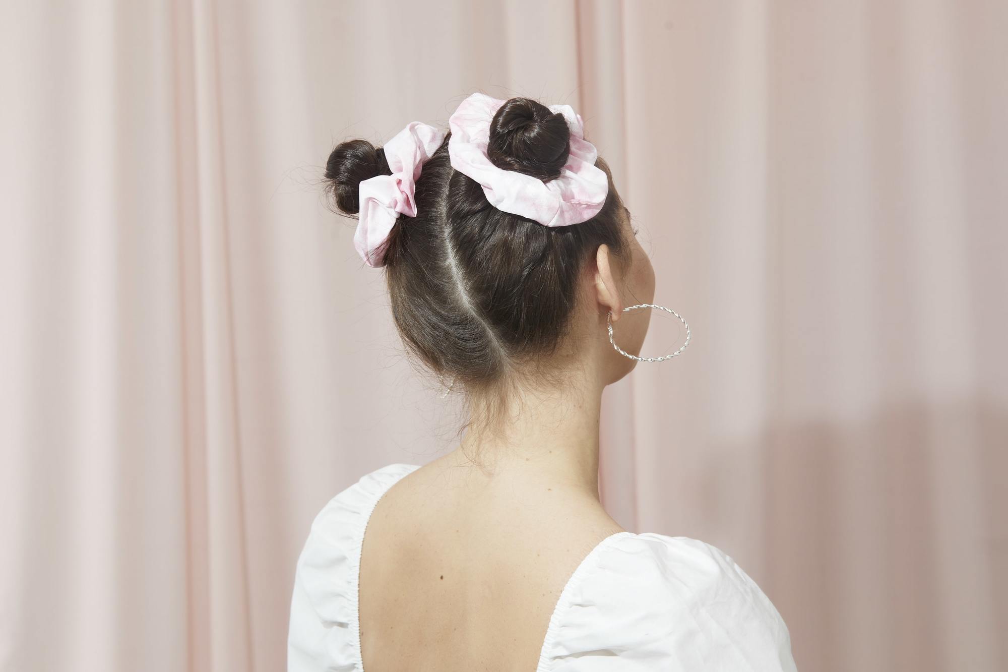 Femme aux cheveux bruns foncés en petits pains de l'espace avec des chouchous