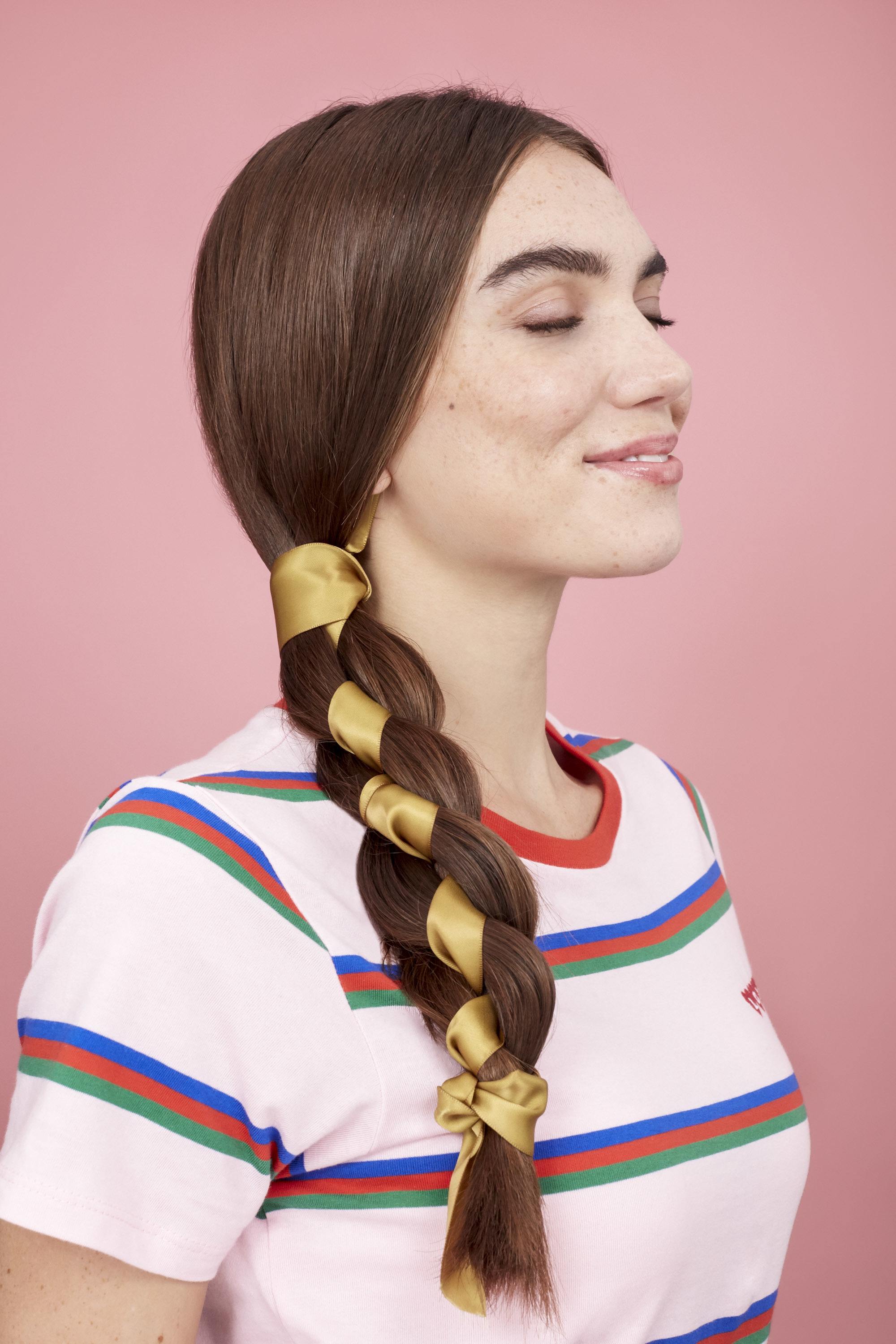Coiffures faciles pour cheveux longs: Femme aux cheveux bruns raides en tresse d'écharpe latérale portant un t-shirt à rayures.