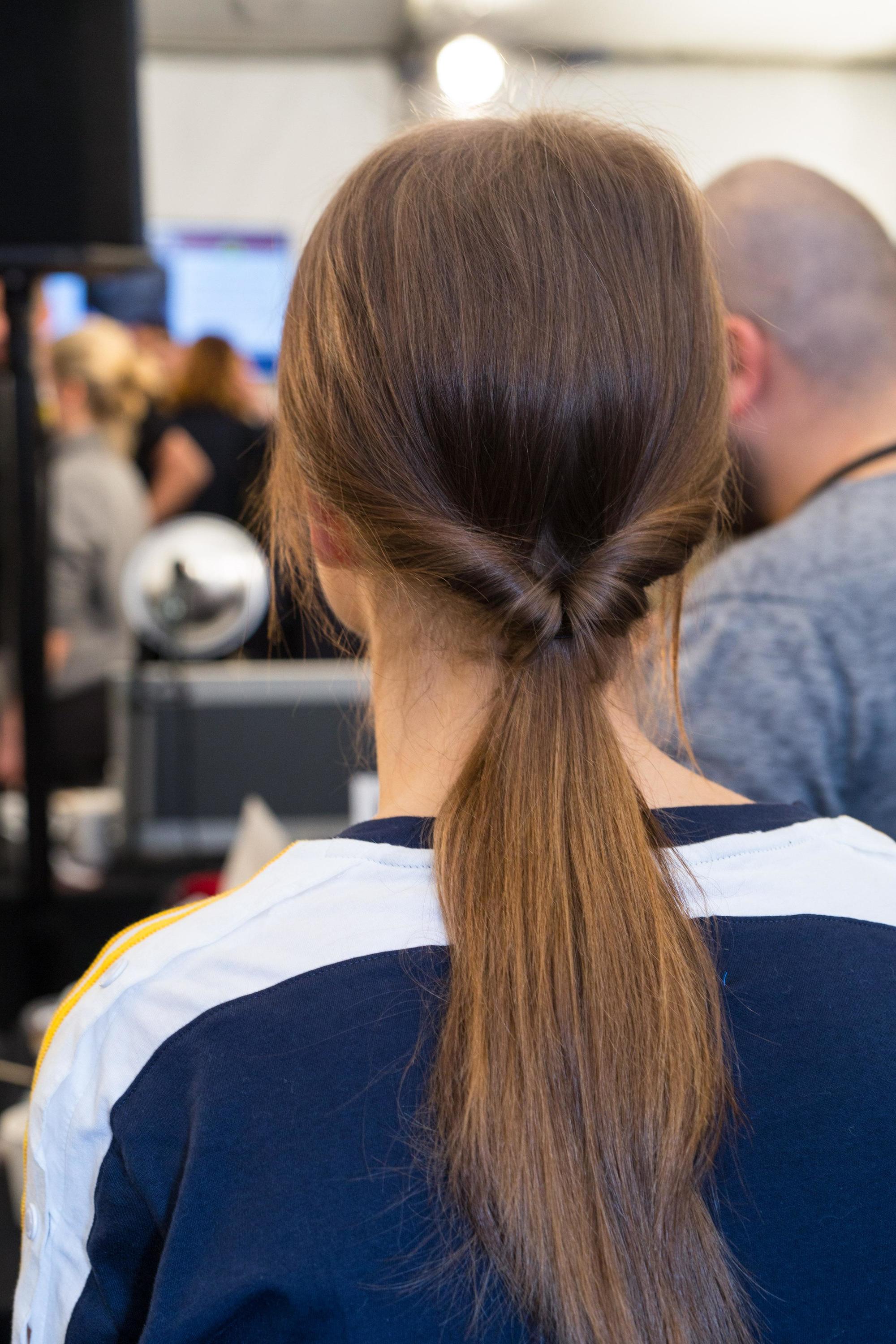 Coiffures faciles pour cheveux longs: Femme aux longs cheveux bruns en queue de cheval torsadée portant un sweat-shirt bleu marine dans les coulisses.