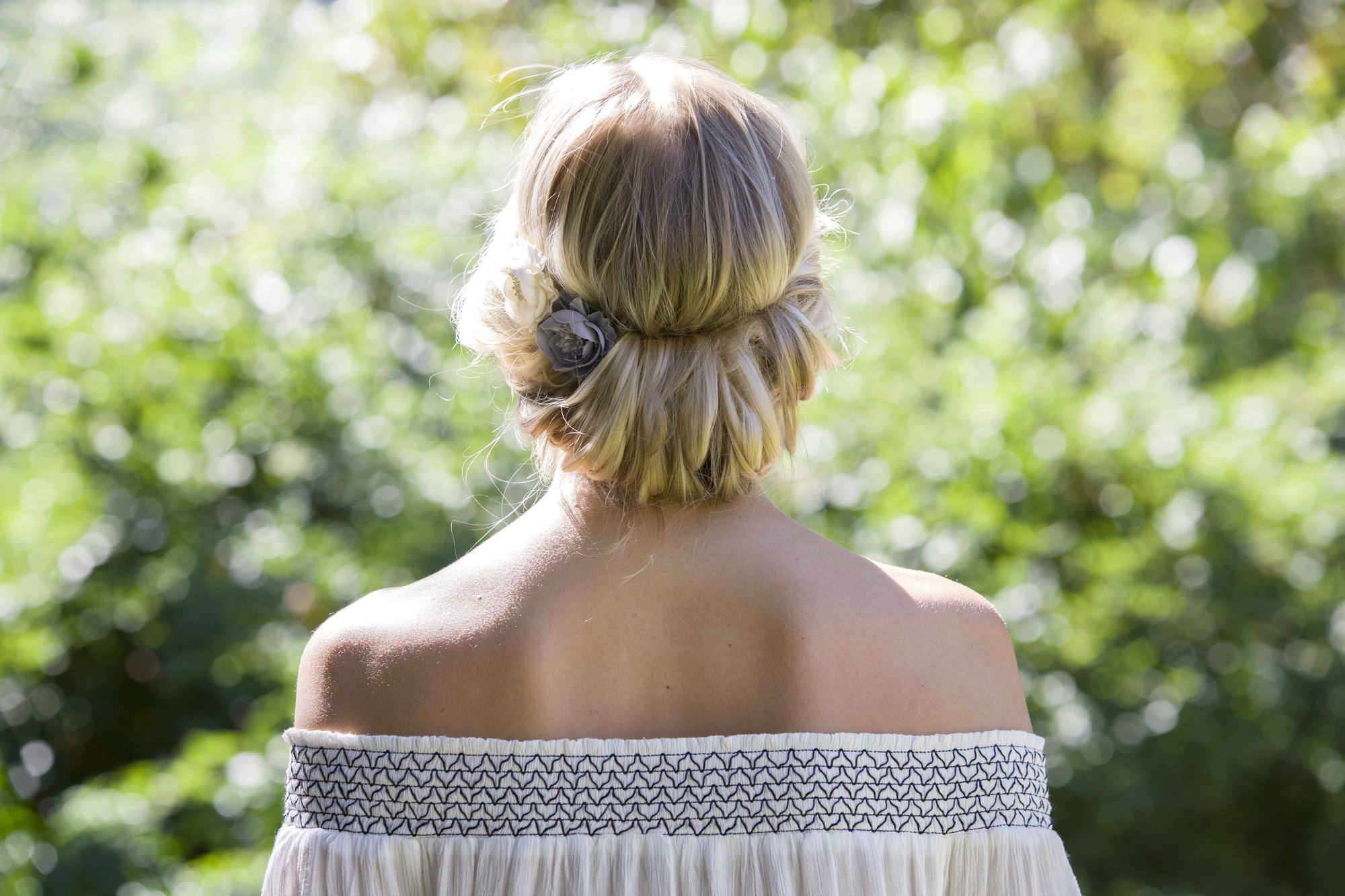 Coiffures faciles pour cheveux longs: Femme aux longs cheveux blonds coiffée d'un chignon serre-tête portant un haut d'été.