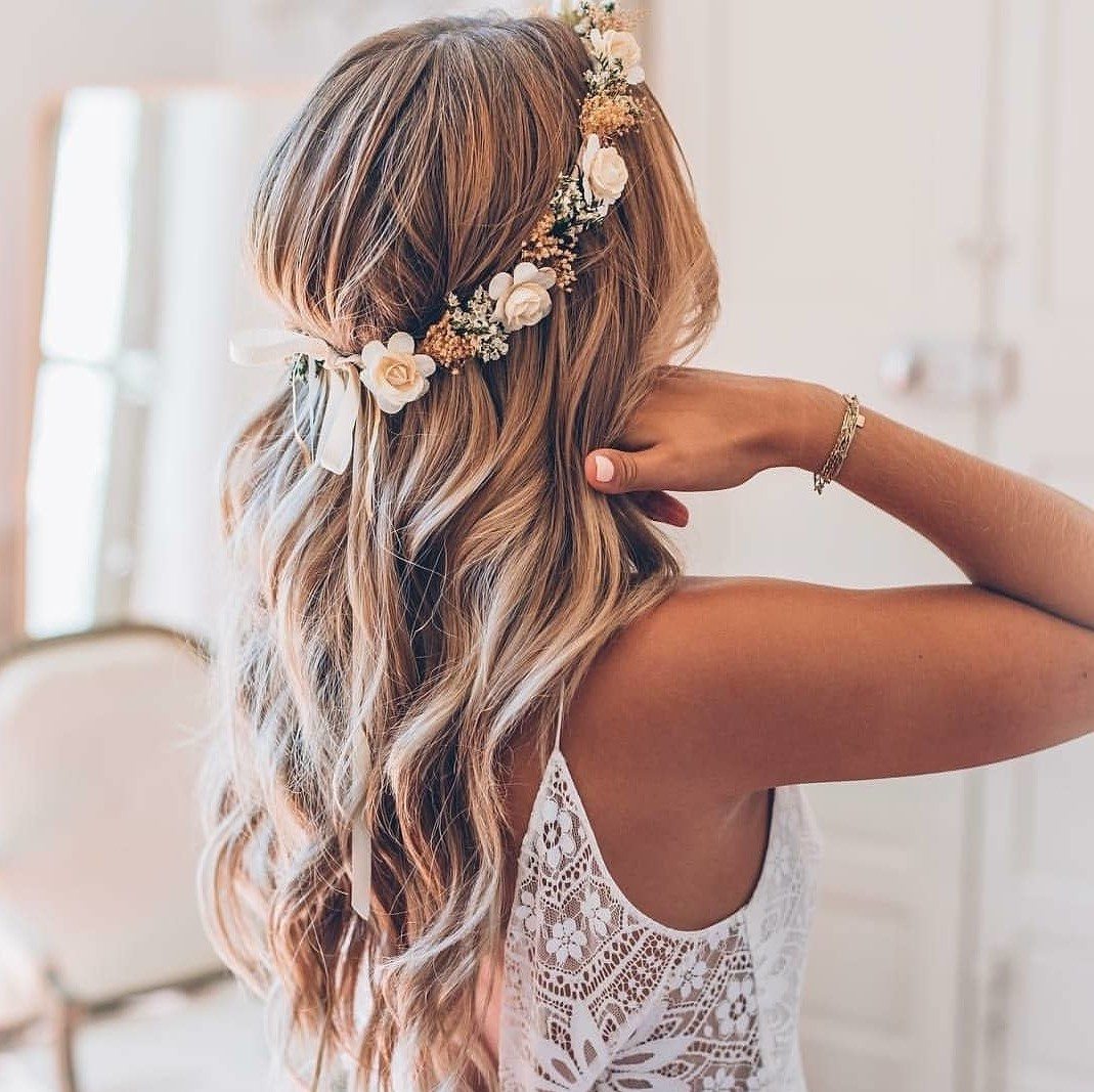 Wedding hairstyles: Woman with long bronde beachy waves with flower crown, wearing wedding dress and posing in a bedroom setting