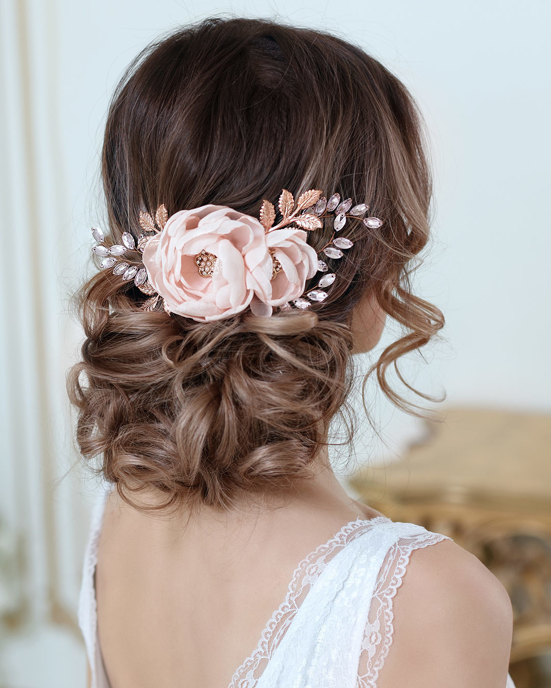 Wedding hairstyles: Woman with dark brown hair with highlights with her hair styled into a messy updo, with flowers in it, wearing a wedding dress