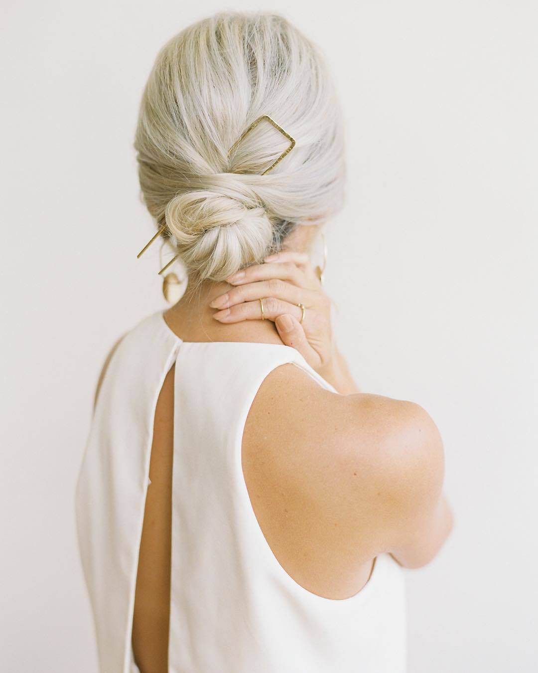Wedding hairstyles: Woman with platinum hair styled into a sleek low bun, wearing a clip