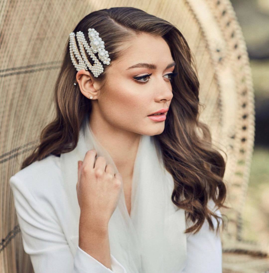 Wedding hairstyles: Woman with long dark brown hair styled into retro glam waves with trendy pearl hair slides