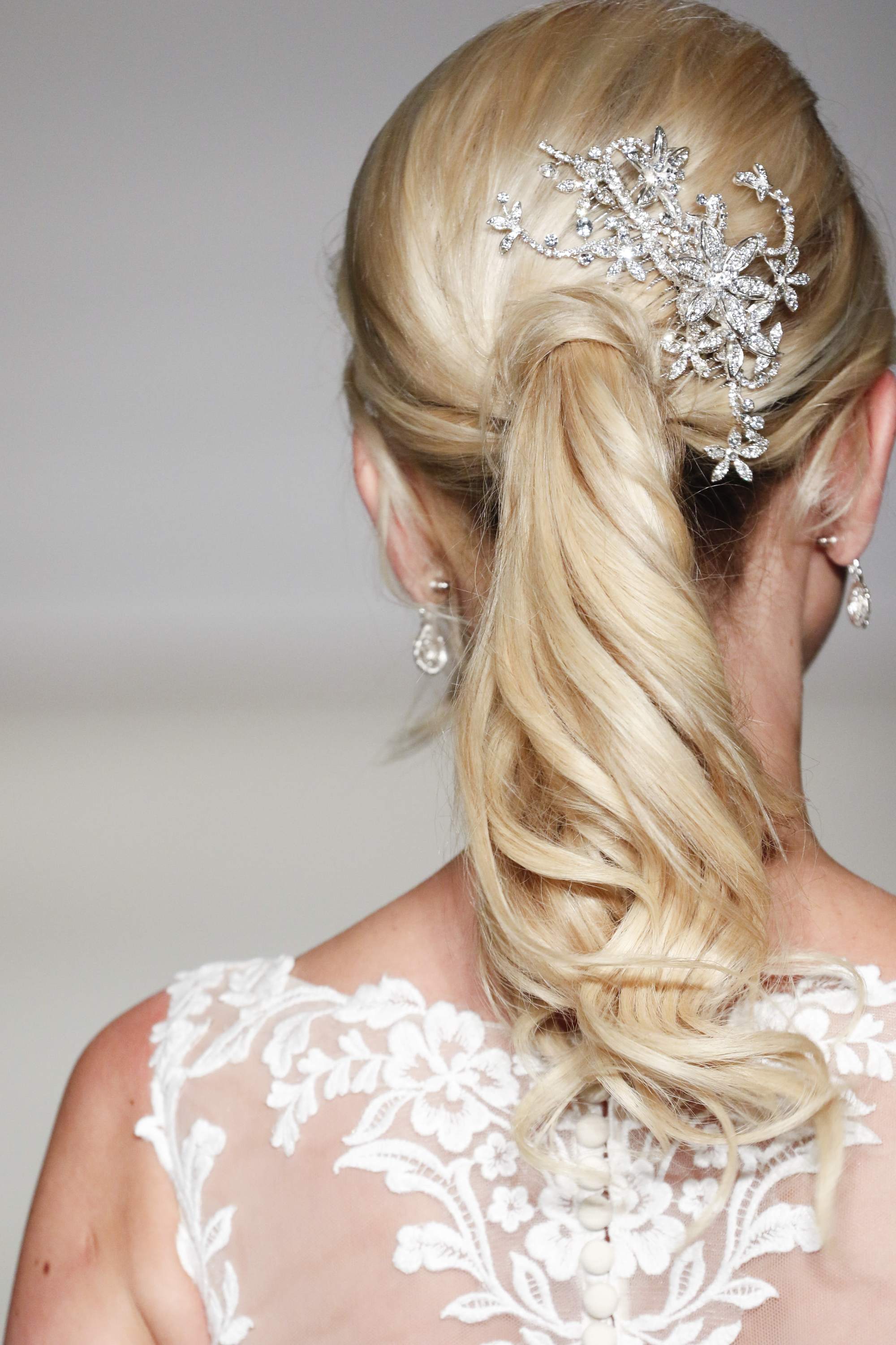 blonde bridal model with her hair in a curly ponytail with a hair accessory