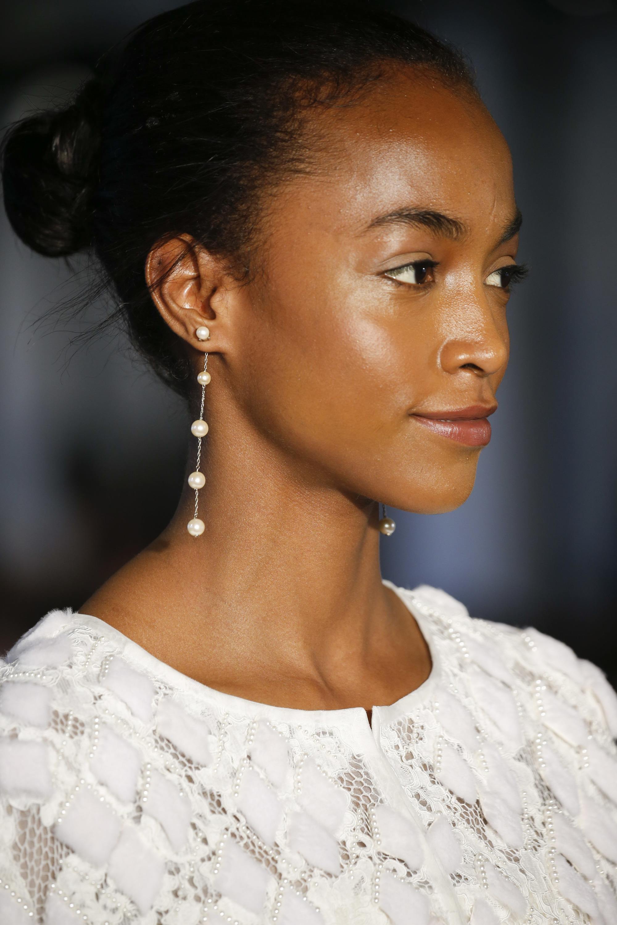 Wedding hairstyles: Model on the runway with a polished and shiny ballerina bun, wearing wedding dress with drop earrings