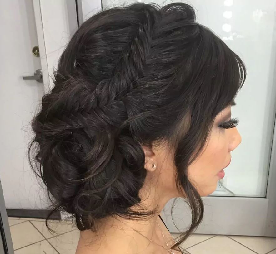 Bridal hairstyles: Fishtail side bun on long dark hair from side profile.
