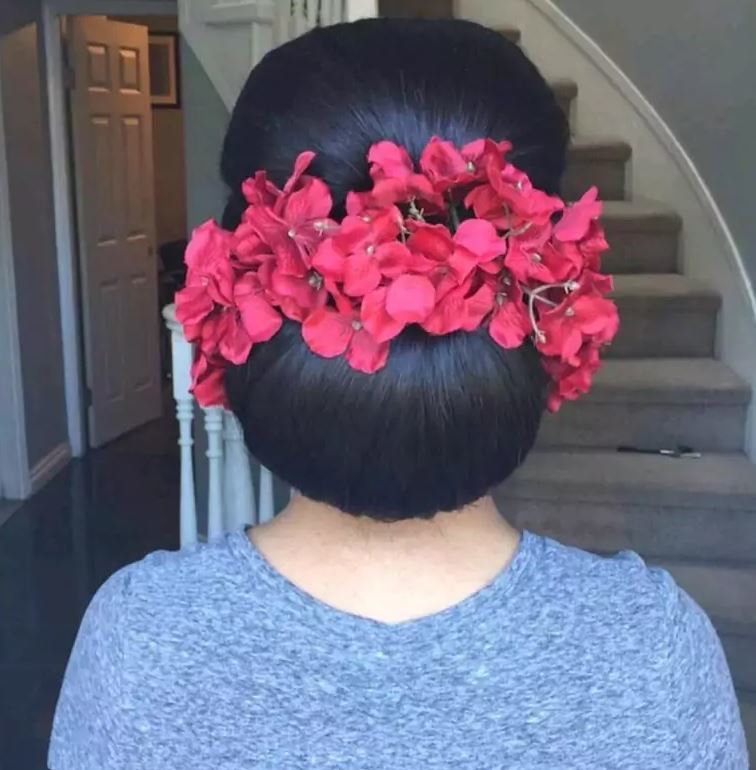 Bridal hairstyles:Woman with dark brown hair styled into floral chignon surrounded by red floral accessories