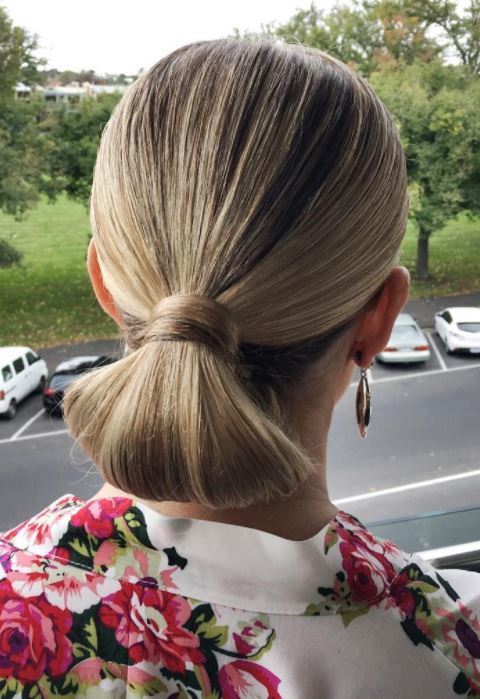 Bridal hairstyles: Woman with golden blonde hair slicked back into a low tuck bun updo