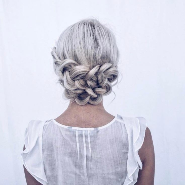 Bridal hairstyles: Woman with silver blonde hair styled into a low braid wrap