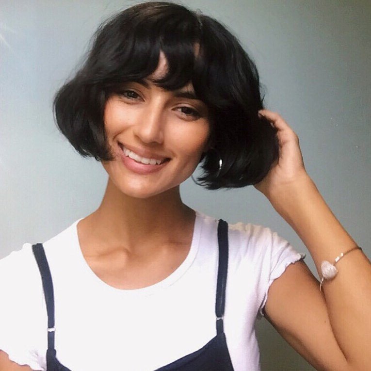 Woman with thick hair cut into a short curled bob style with bangs