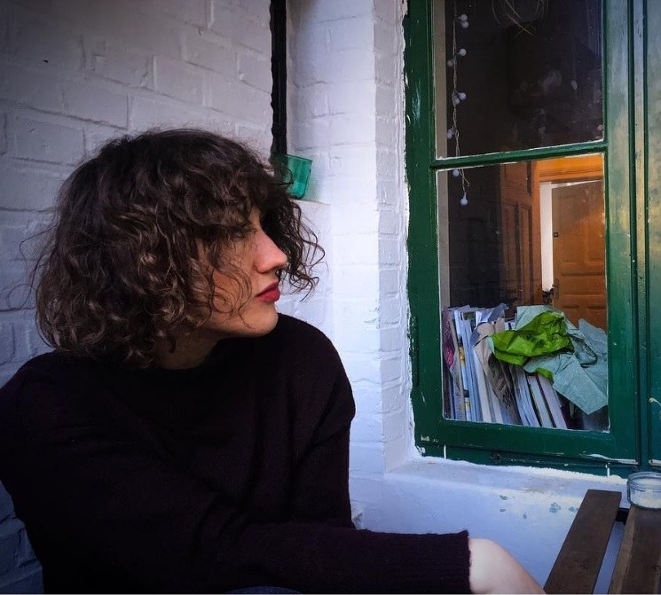 woman wearing a black jumper with brunette curly french bob hair