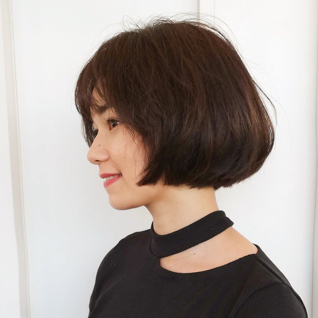 Woman with thick messy dark brown bob with wispy fringe