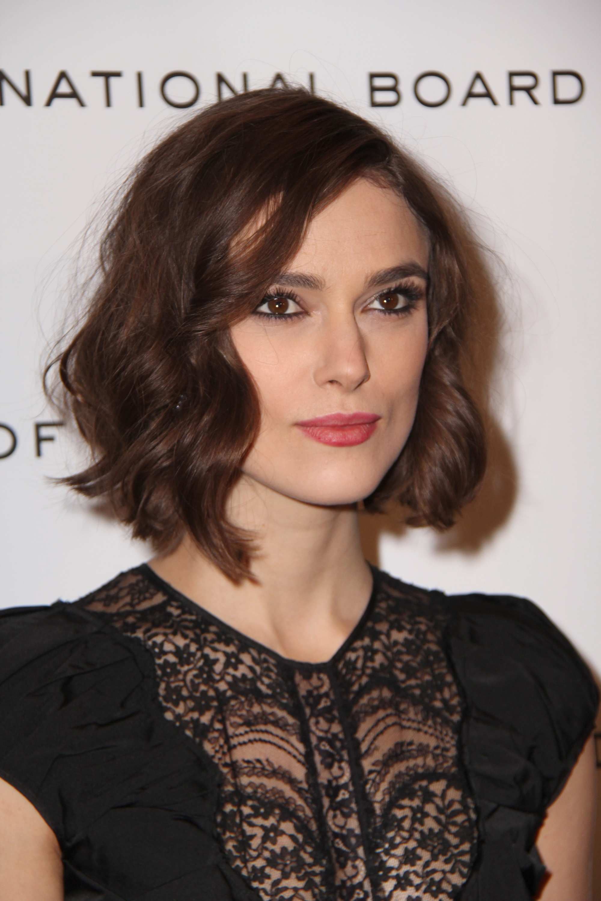 Keira Knightley with a brunette wavy bob with side-swept curled bangs
