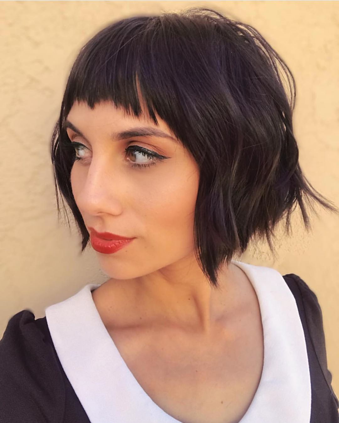 Woman with dark brown wavy short bob with micro fringe