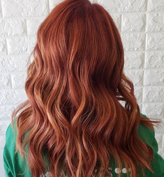 Faits saillants cuivrés: Vue arrière d'une rousse aux cheveux bouclés cuivrés, vêtue d'un haut vert