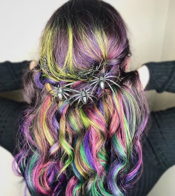 Coiffures d'Halloween : Plan arrière d'une femme aux longs cheveux colorés en vert, violet, rose et bleu, coiffée en une coiffure tressée à mi-hauteur, avec des accessoires de coiffure d'Halloween en forme d'araignée