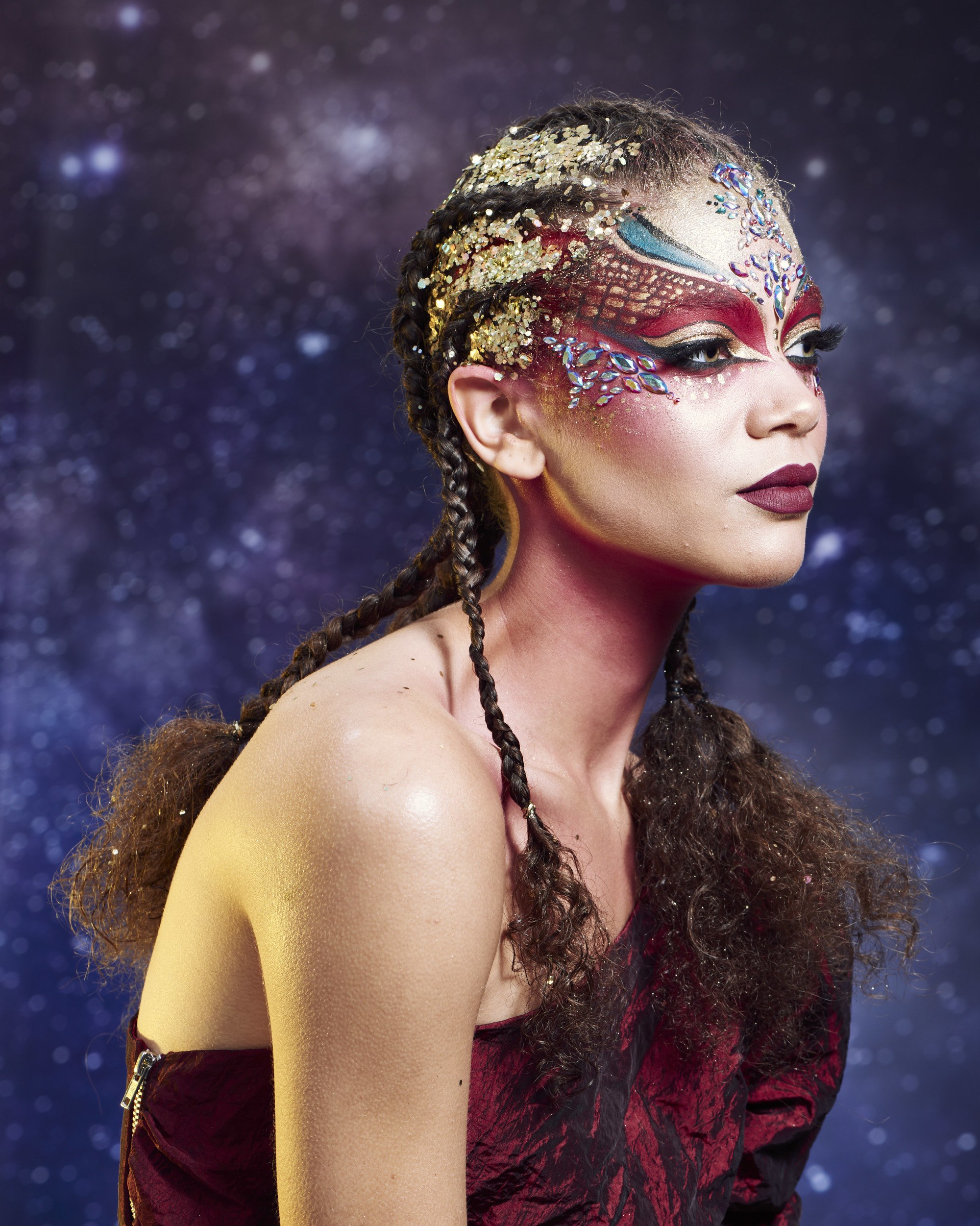 Coiffures d'Halloween : Femme au dos droit avec des cornrows aux extrémités défaissées, avec des paillettes dorées sur le cuir chevelu