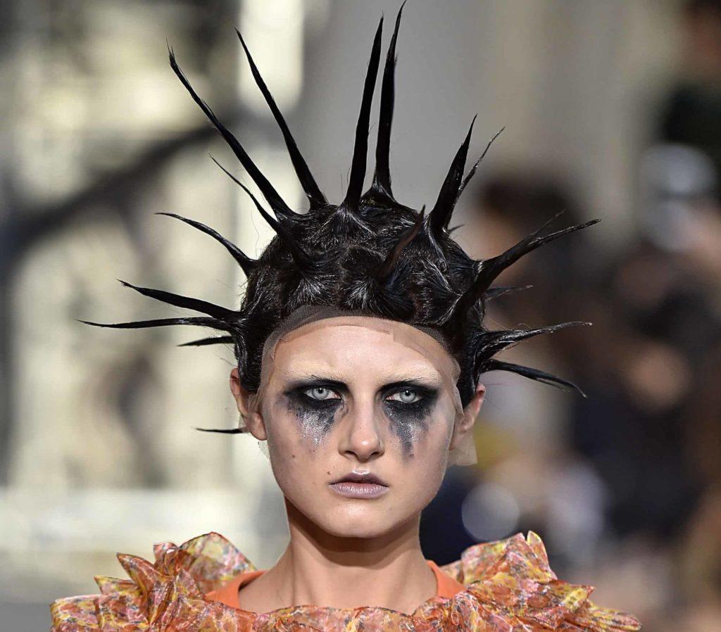 mannequin de défilé avec des cheveux noirs en longs pics et un maquillage taché