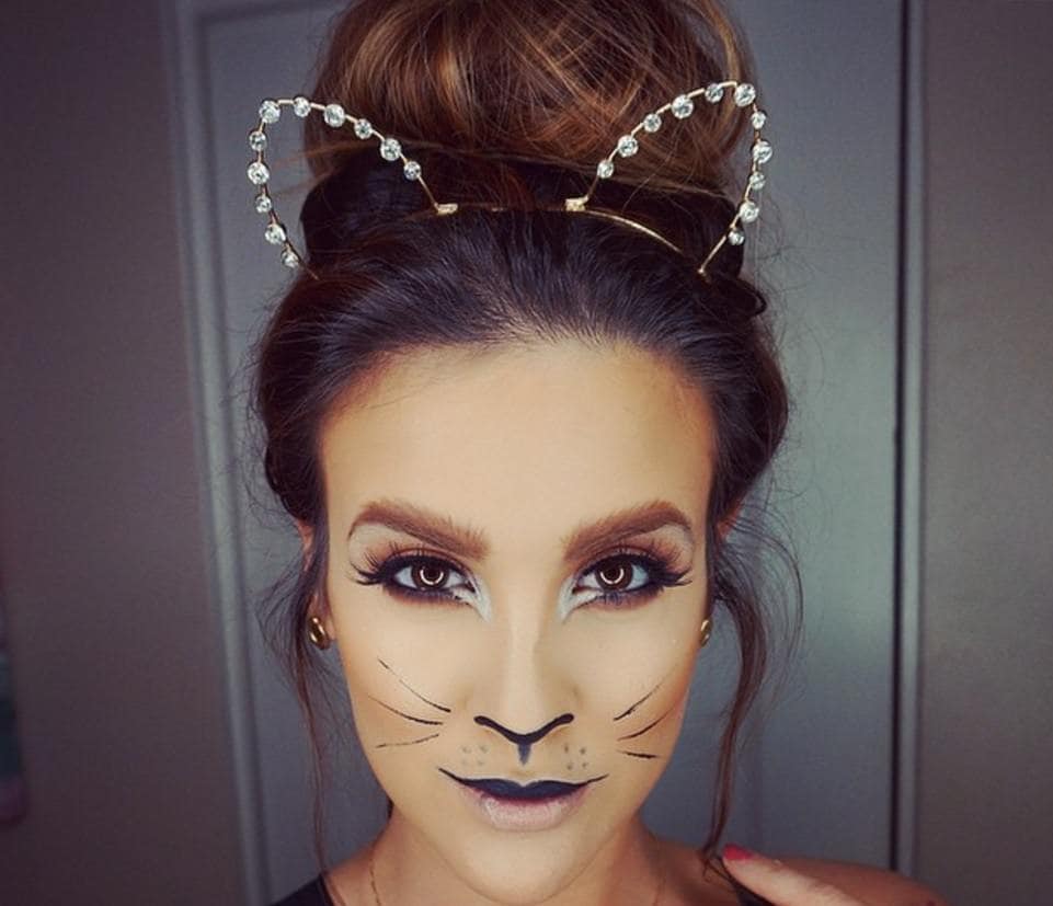 femme aux cheveux bruns dans un grand chignon avec un maquillage de chat et portant un bandeau pour les oreilles de chat