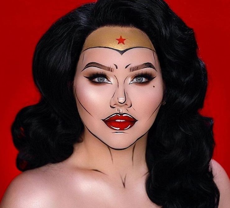 Coiffures d'Halloween : Femme habillée en Wonder Woman, avec de longs cheveux noirs ondulés, portant du maquillage pop art Wonder Woman sur le visage tout en posant pour une photo