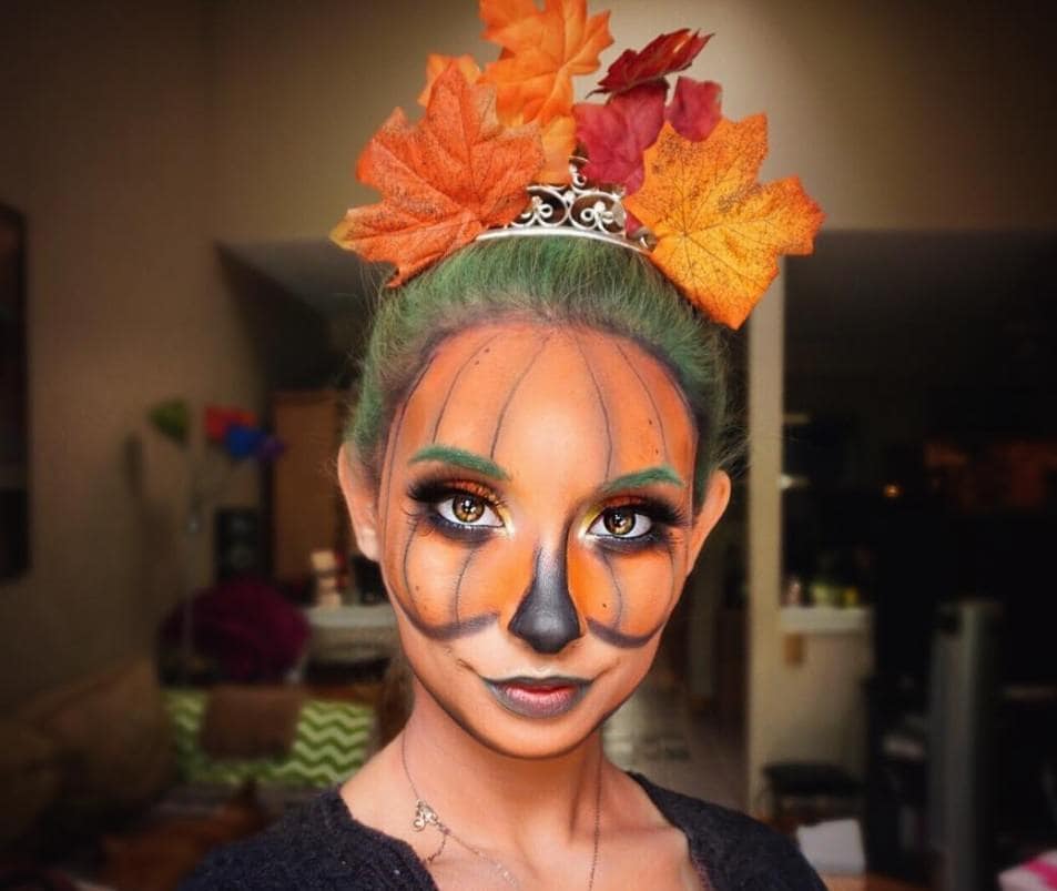 femme au visage peint en citrouille et aux cheveux verts avec des feuilles d'automne