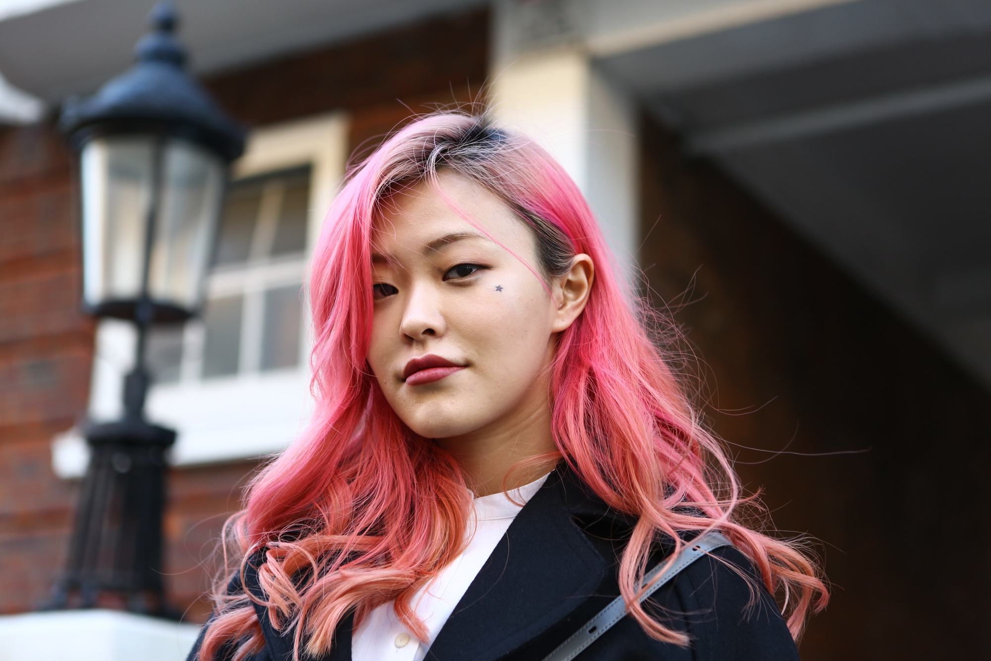 Fille asiatique aux cheveux roses teints se tenant à l'extérieur