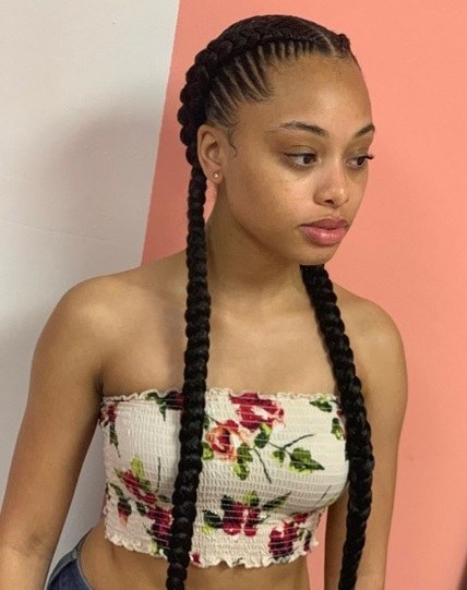 Femme aux cheveux longs bruns foncés, coiffée de deux tresses de cornouiller