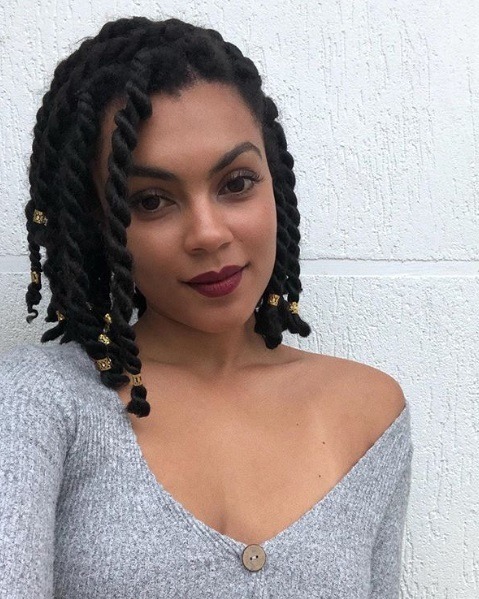 Femme brune au bob length torsadé avec des poignets dorés
