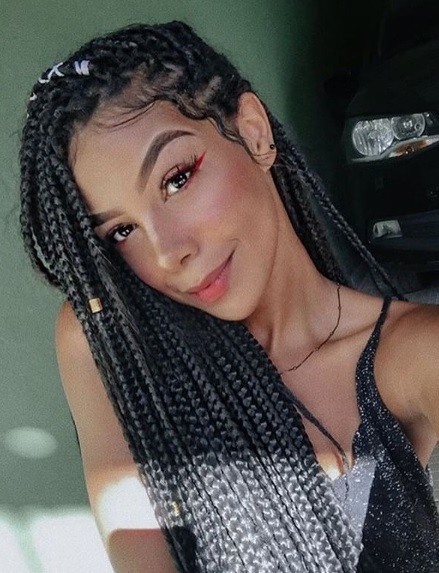 Femme avec de longues tresses brunes en forme de boîte portées sur un côté