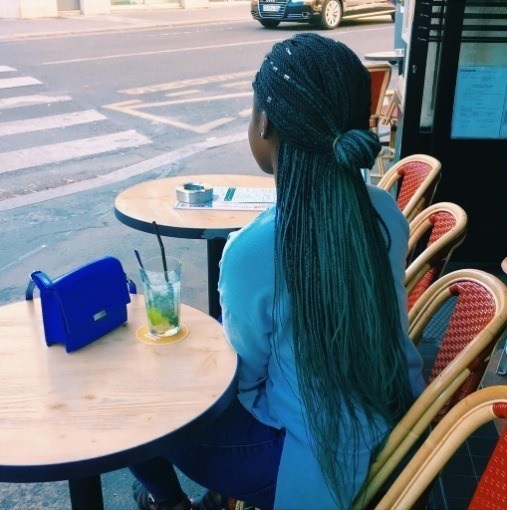 femme avec des tresses bleues maigres dans un chignon à moitié relevé 