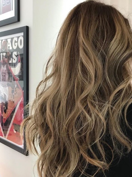 Points forts partiels : Vue de dos d'une femme aux longs cheveux bouclés brun moyen avec des mèches blondes