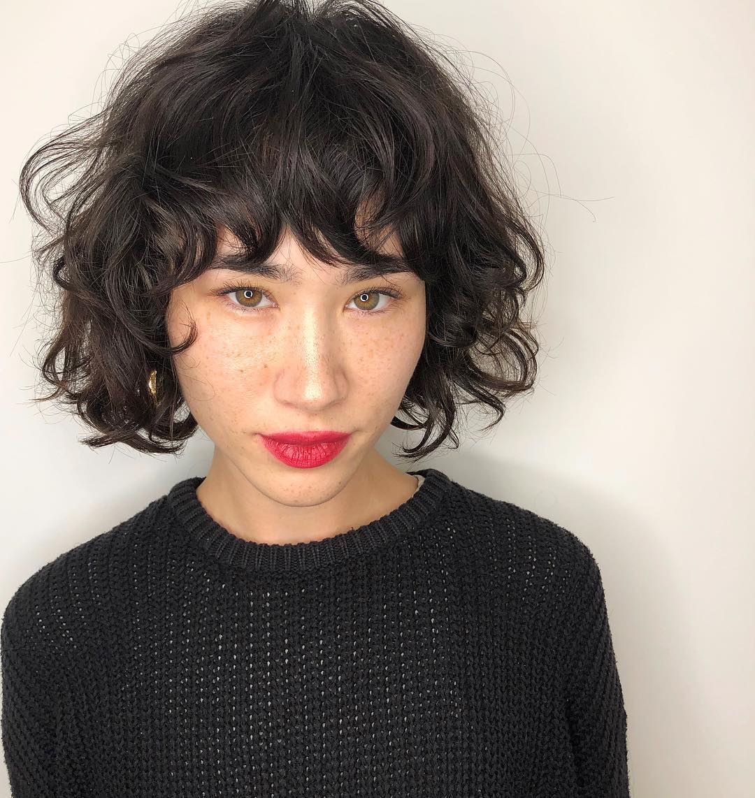 Femme avec un bob sombre et court avec une frange désordonnée