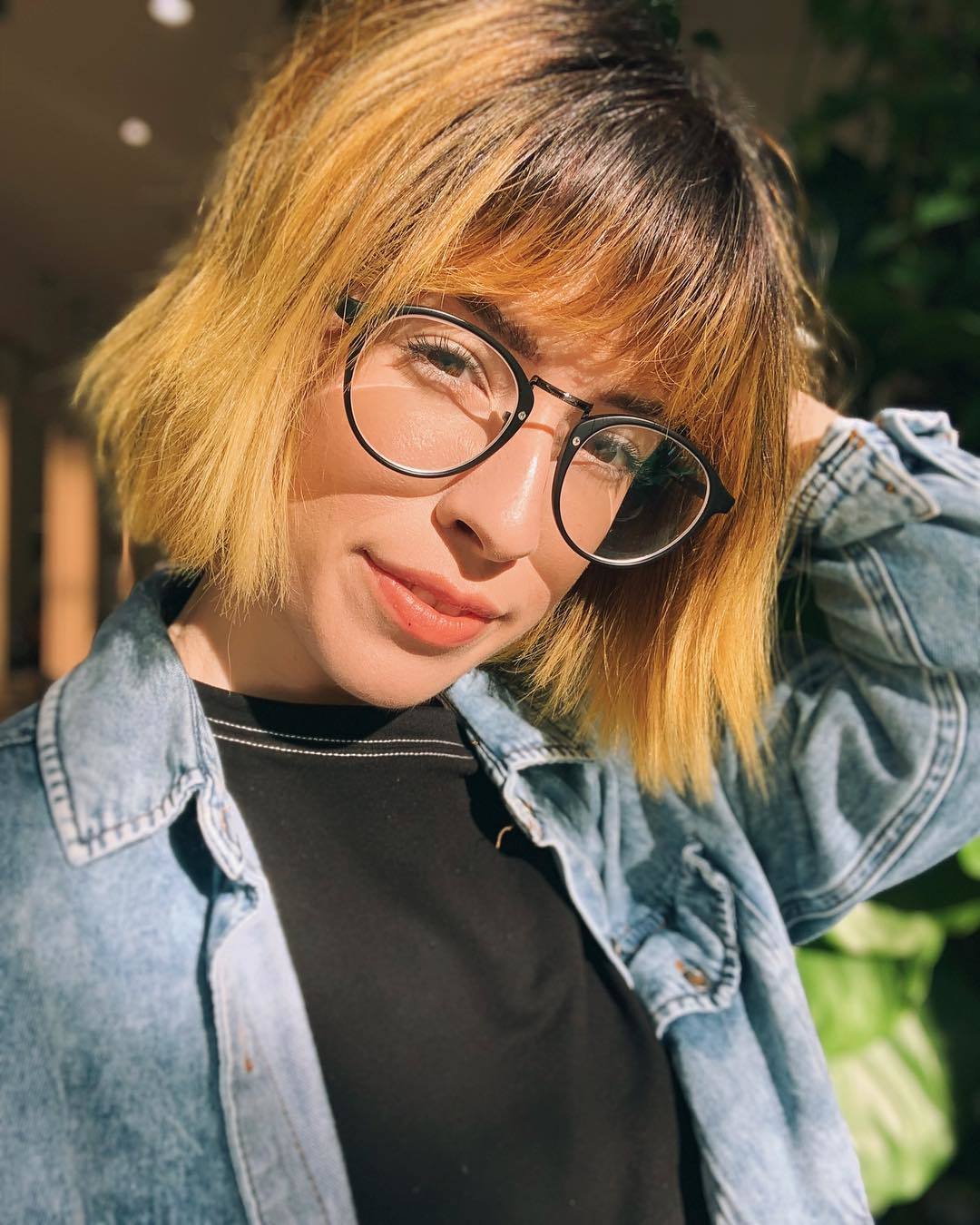 Femme aux racines sombres et au bob court orange avec une frange