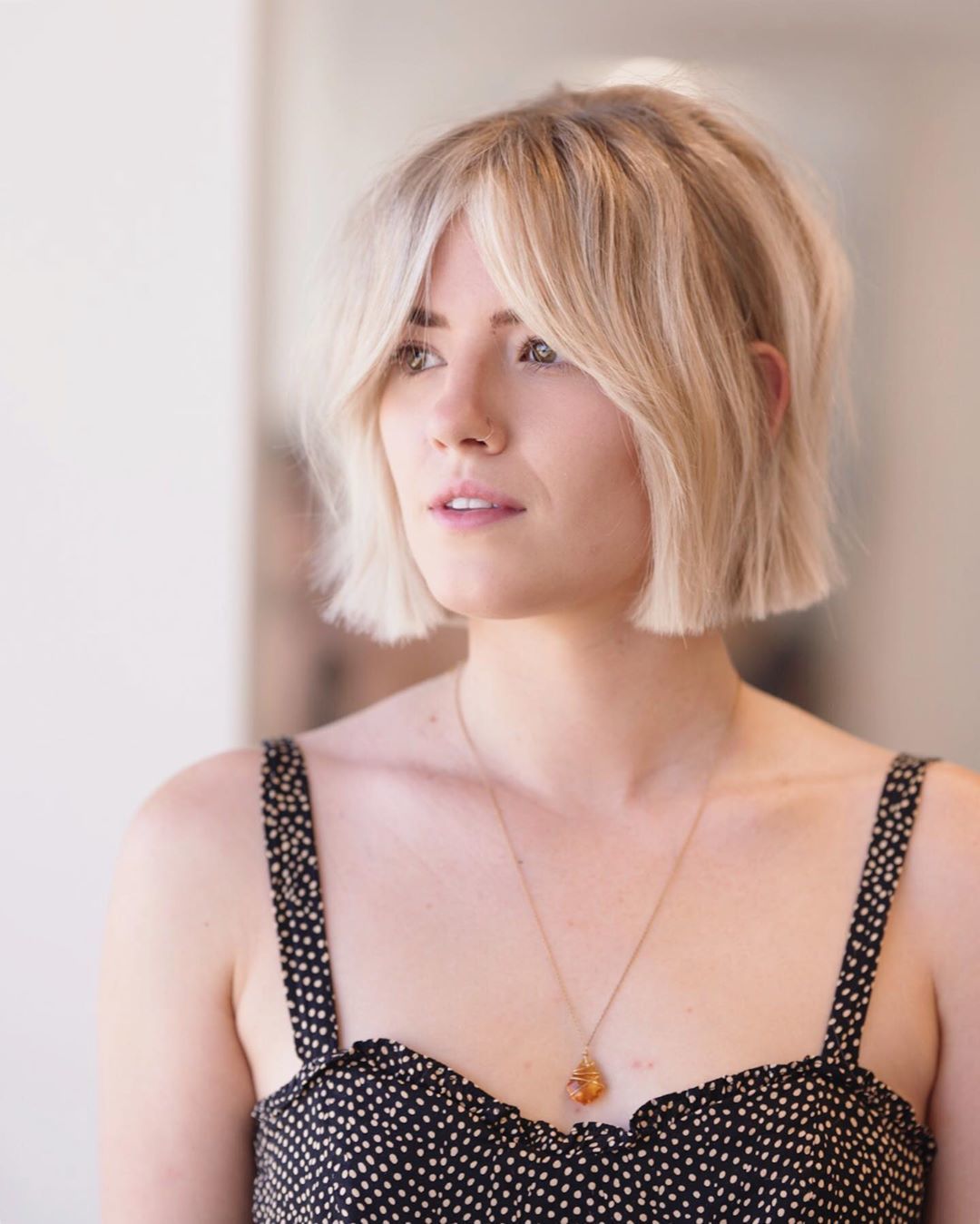 Femme avec un bob court blond naturel à la frange fendue