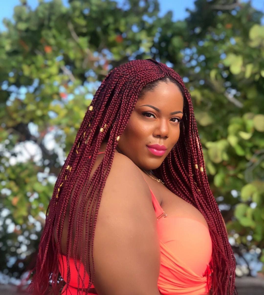 Femme portant une perruque rouge en cornrow avec des manchettes dorées