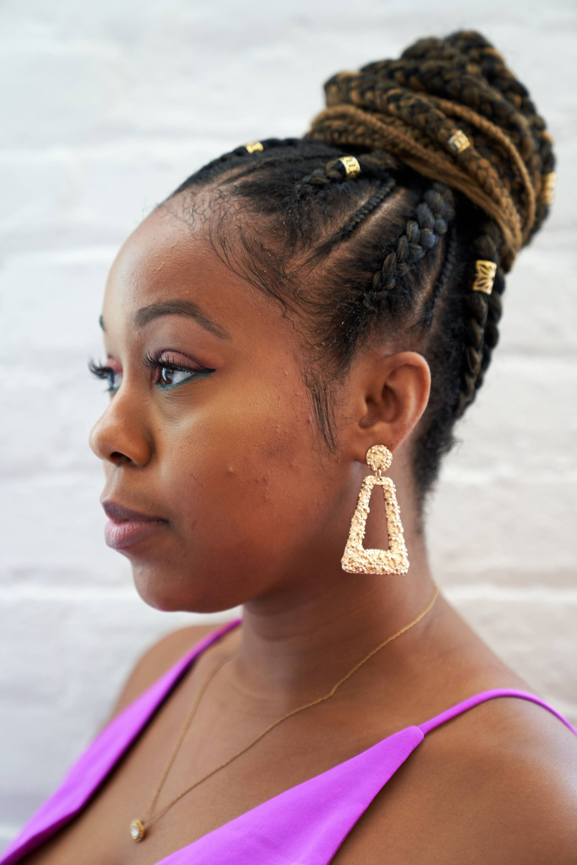 Femme avec des tresses de cornrow dans un chignon aux poignets dorés