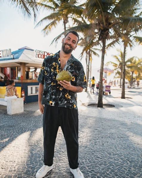 matthewzorpas : homme barbu portant une chemise tropicale et tenant une noix de coco sur la plage