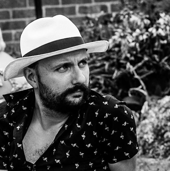 Image en noir et blanc d'un homme barbu portant un chapeau blanc