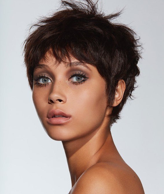 femme avec une coupe de cheveux de lutin des années 60, brun foncé et désordonné